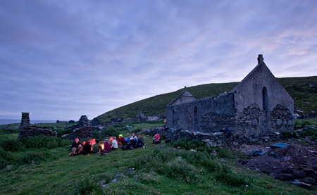 Team members end their day around a campfire made from driftwood in front of the ruins of St. Leo's church, Inishark Island, Ireland.